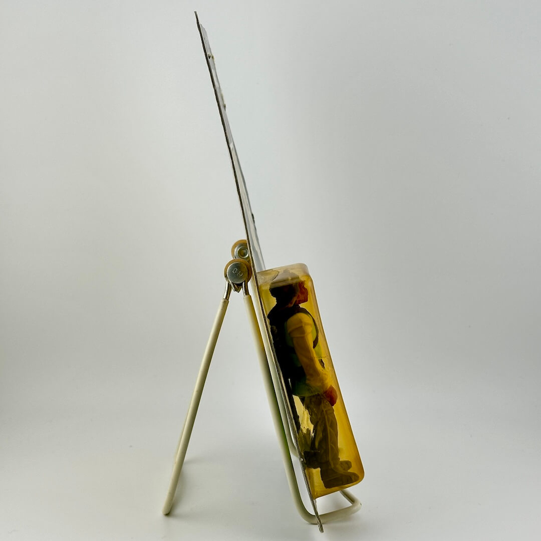 Side view of Star Wars action figure in packaging on easel against white background.