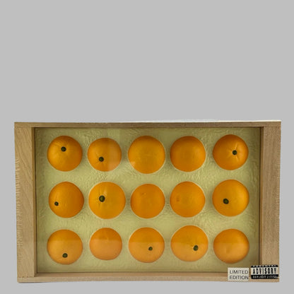 Plastic wrapped wooden fruit crate with blue label on side, & fake oranges in top. Top view.