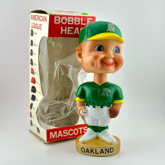 Bobblehead figure of a baseball player in green uniform with 'Oakland' on base, next to packaging.