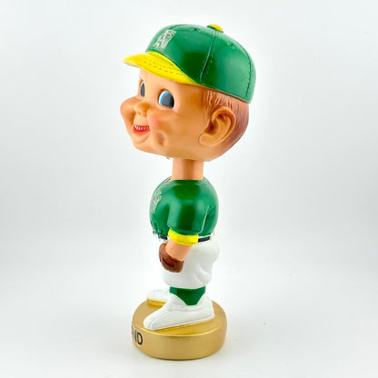 Bobblehead figure of a baseball player in green and white uniform with a green cap on a white background