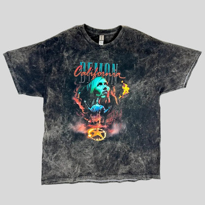A black acid-wash graphic t-shirt featuring a central illustration of a woman's face with flames and the text 'California Demon.'