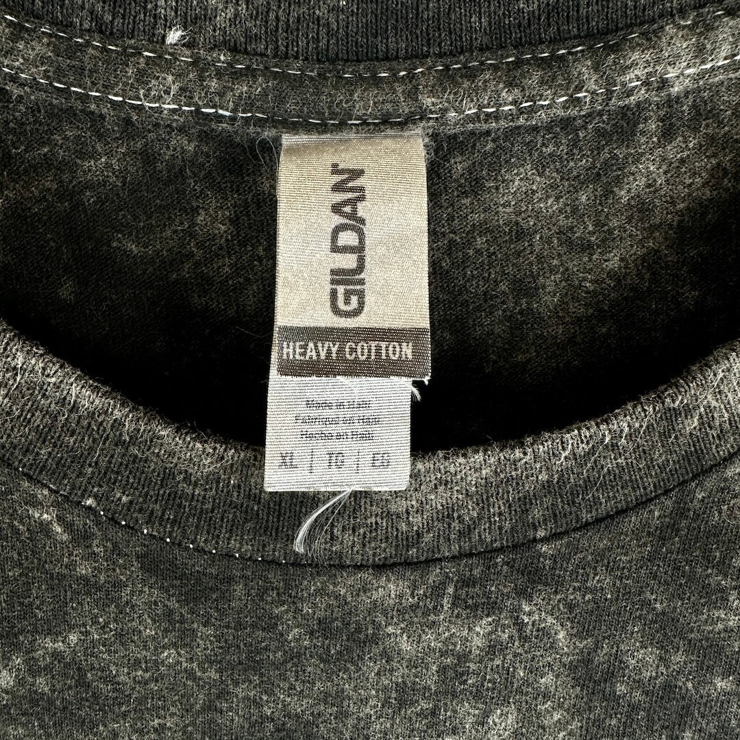 Close-up of a Gildan heavy cotton t-shirt showing the inner neck label and the dark gray mineral-wash fabric texture.
