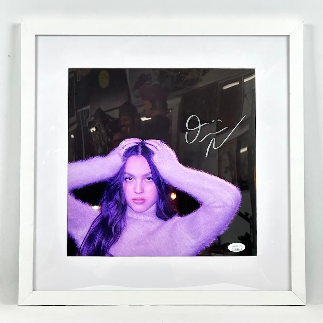 Framed photo of a Olivia Rodrigo with hands on her head in a white frame