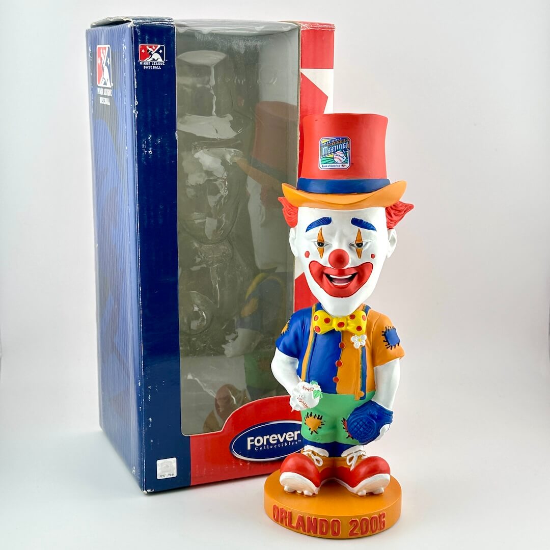 Colorful clown figurine with a top hat and bow tie, standing next to a branded box.