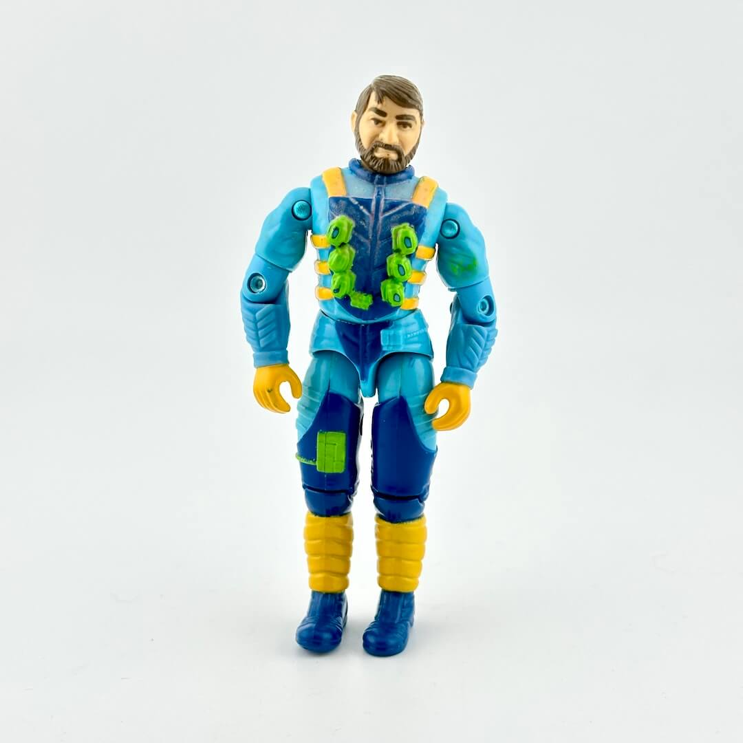 GI Joe action figure in blue flight suit with yellow and green accents, photographed on white background. 