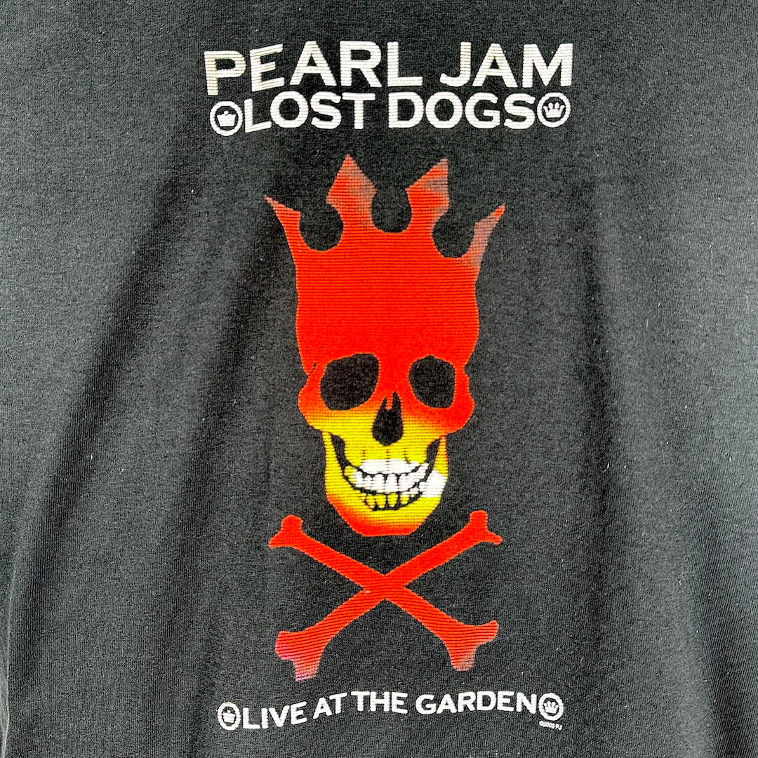 Close up of black t-shirt's graphic of crowned skull in red and yellow, white text above and below.