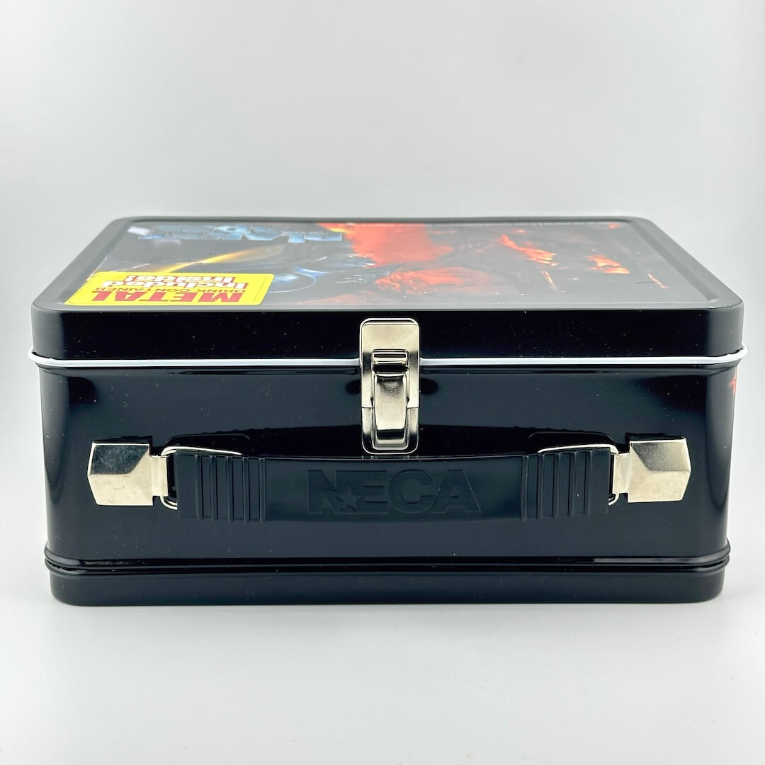 Top view of metal lunchbox with black background and black plastic handle, and silver latch. 