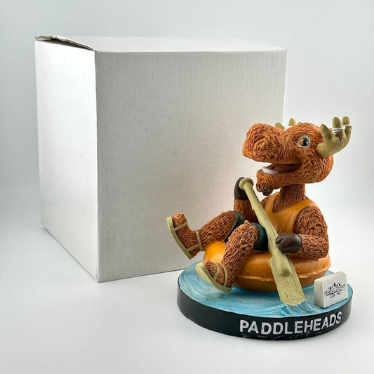 Figurine of a moose on a tube with a paddle, branded 'Paddleheads', in front of a white box.