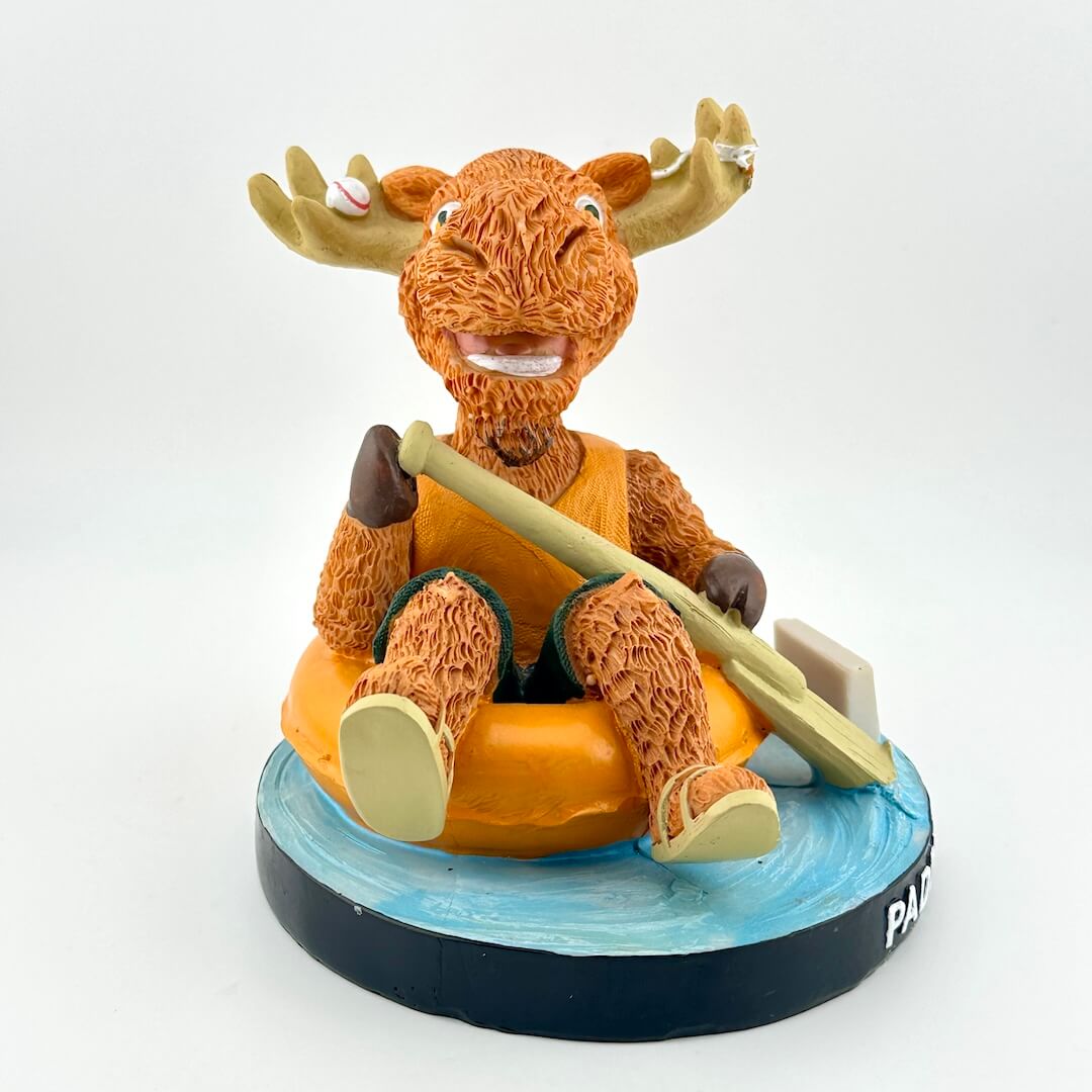 Figurine of a moose in an orange life jacket with a paddle on a white background