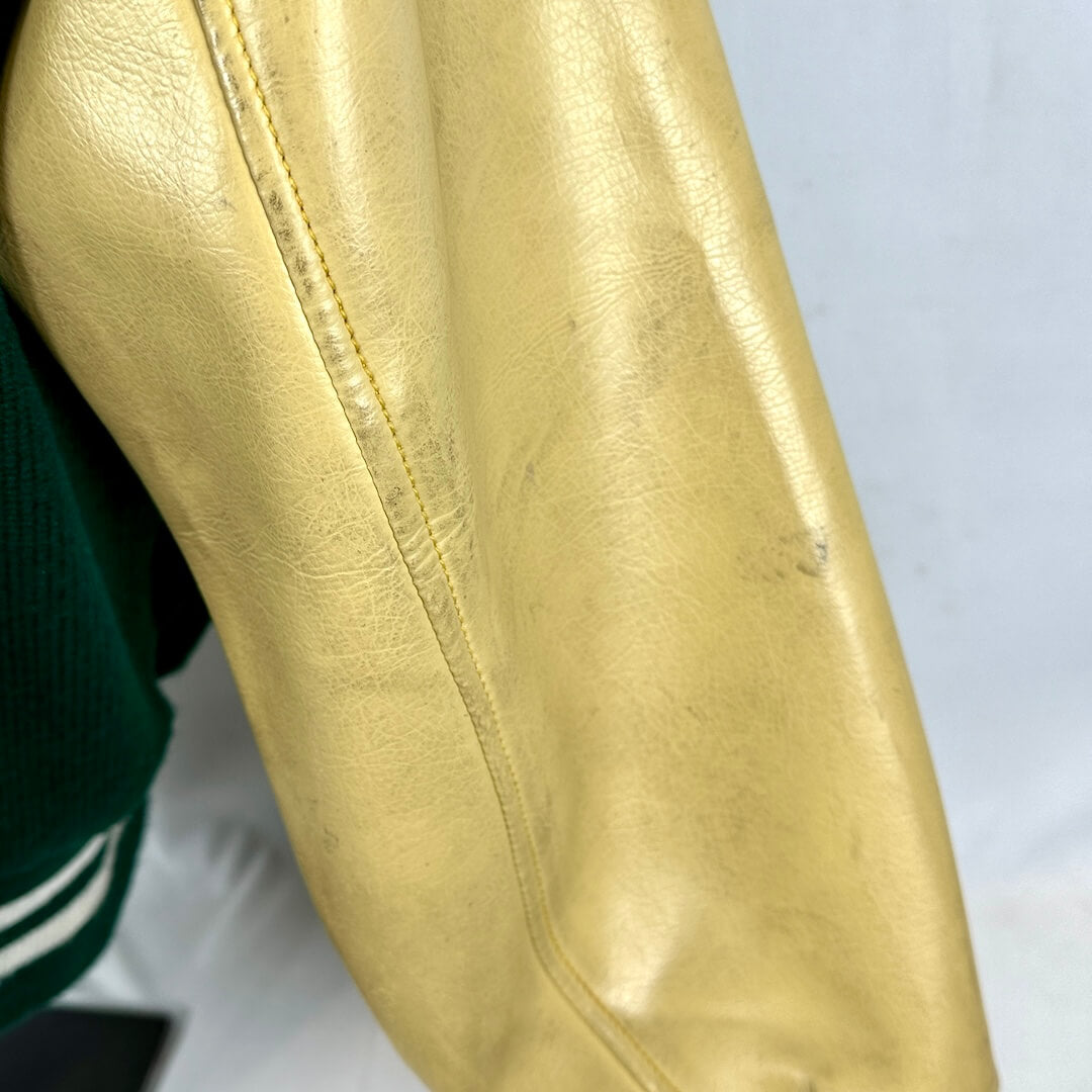 Close-up of a gold leather jacket sleeve with a white background