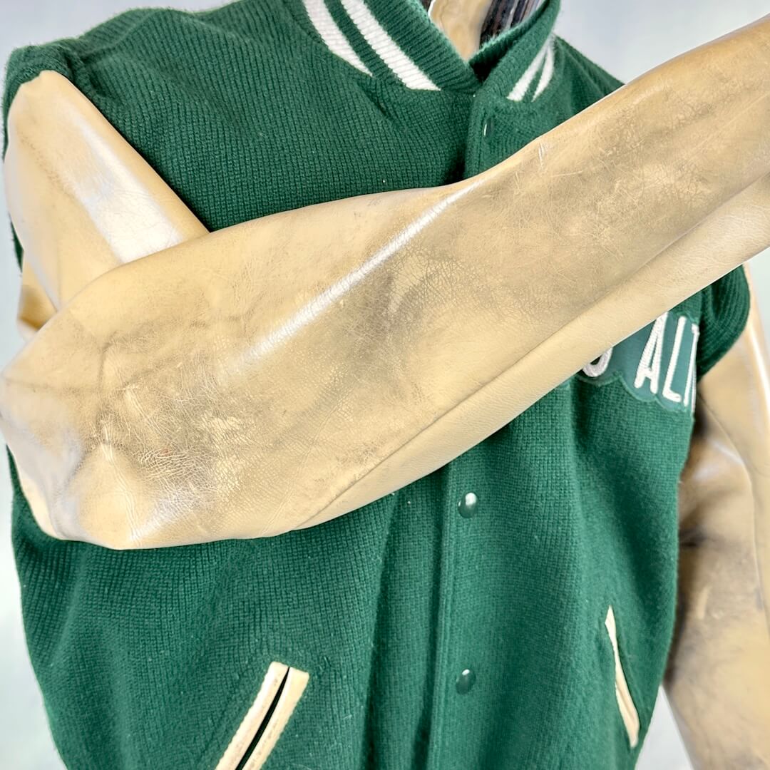 Green varsity jacket with beige accents on a mannequin against a white background