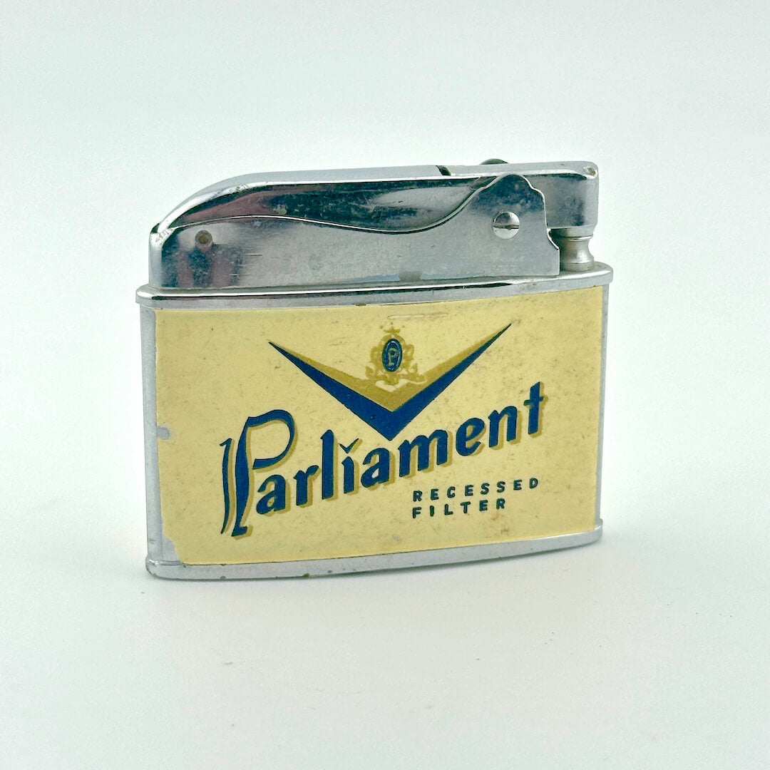 A vintage Parliament lighter with a cream-colored front faceplate, and a polished silver metal body and lid.