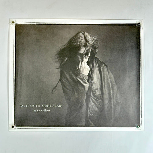 black and white with Patti Smith in leather jacket touching her face with artist and album info to left.