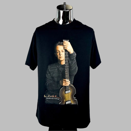 Black short sleeved t-shirt with image of McCartney holding guitar upright with his name in orange at bottom left. 