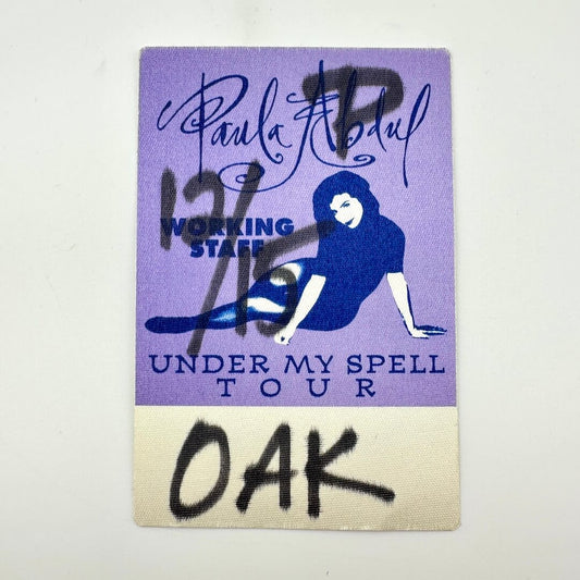 Purple and beige backstage pass with text and a logo, featuring 'Paula Abdul' and 'Under My Spell Tour'.