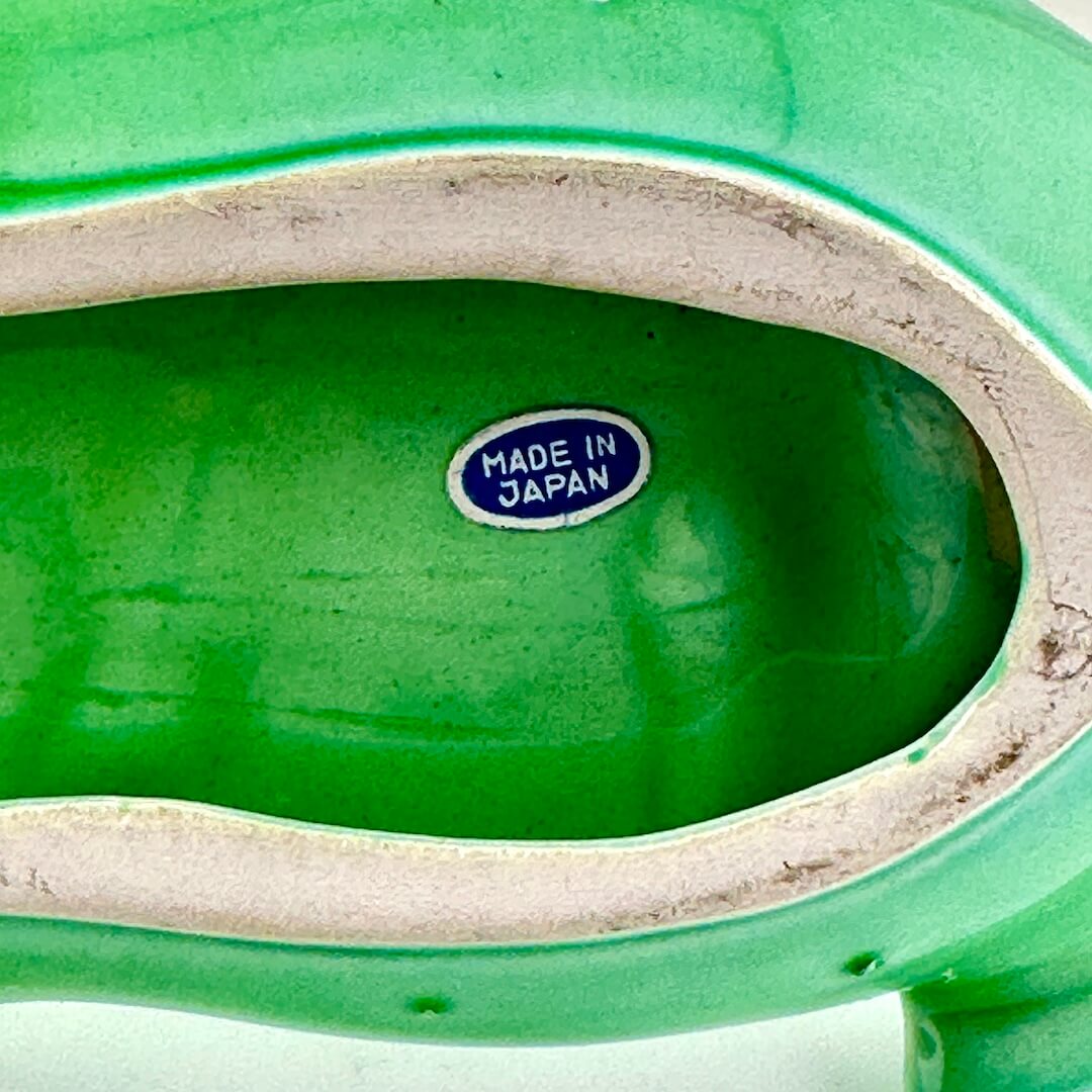 Close-up of the interior base of a glossy green ceramic object, showing a small blue and white 'MADE IN JAPAN' sticker.