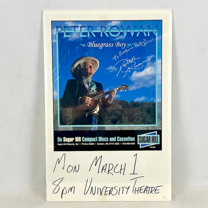 Concert poster for Peter Rowan wrapped in plastic with handwritten event details at bottom. 