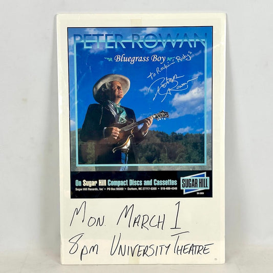 Concert poster for Peter Rowan wrapped in plastic with handwritten event details at bottom. 