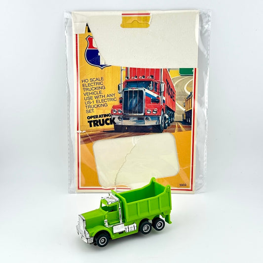 Green toy truck in front of its packaging on a white background