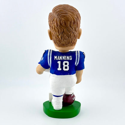 Football player bobblehead in blue jersey holding white helmet against white background. 