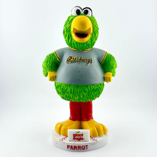 Green parrot mascot figurine with gray shirt and red legs on a white background
