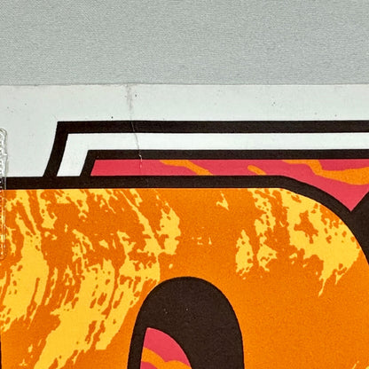 Close-up of a stylized letter 'T' with orange, pink, and black colors on a textured gray background.