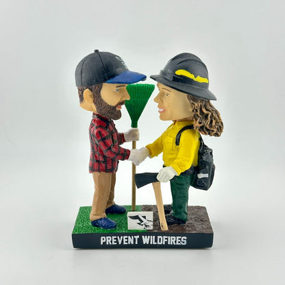 Bobbleheads of a man and woman in outdoor gear with 'Prevent Wildfires' text on a white background