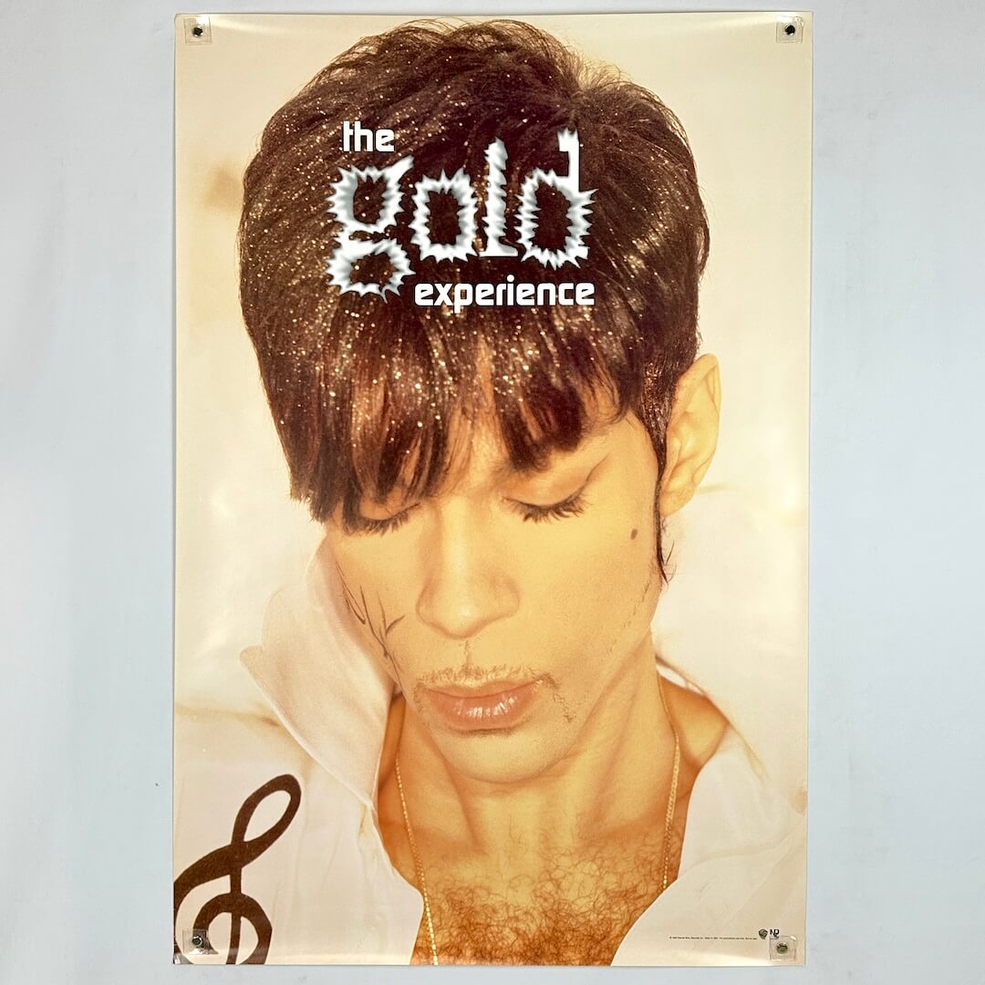 Poster with Prince looking down with  glitter in his hair and gold hue to entire poster. 