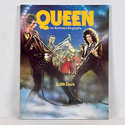 Queen: An Illustrated Biography book with artist depiction of band playing music against white background.