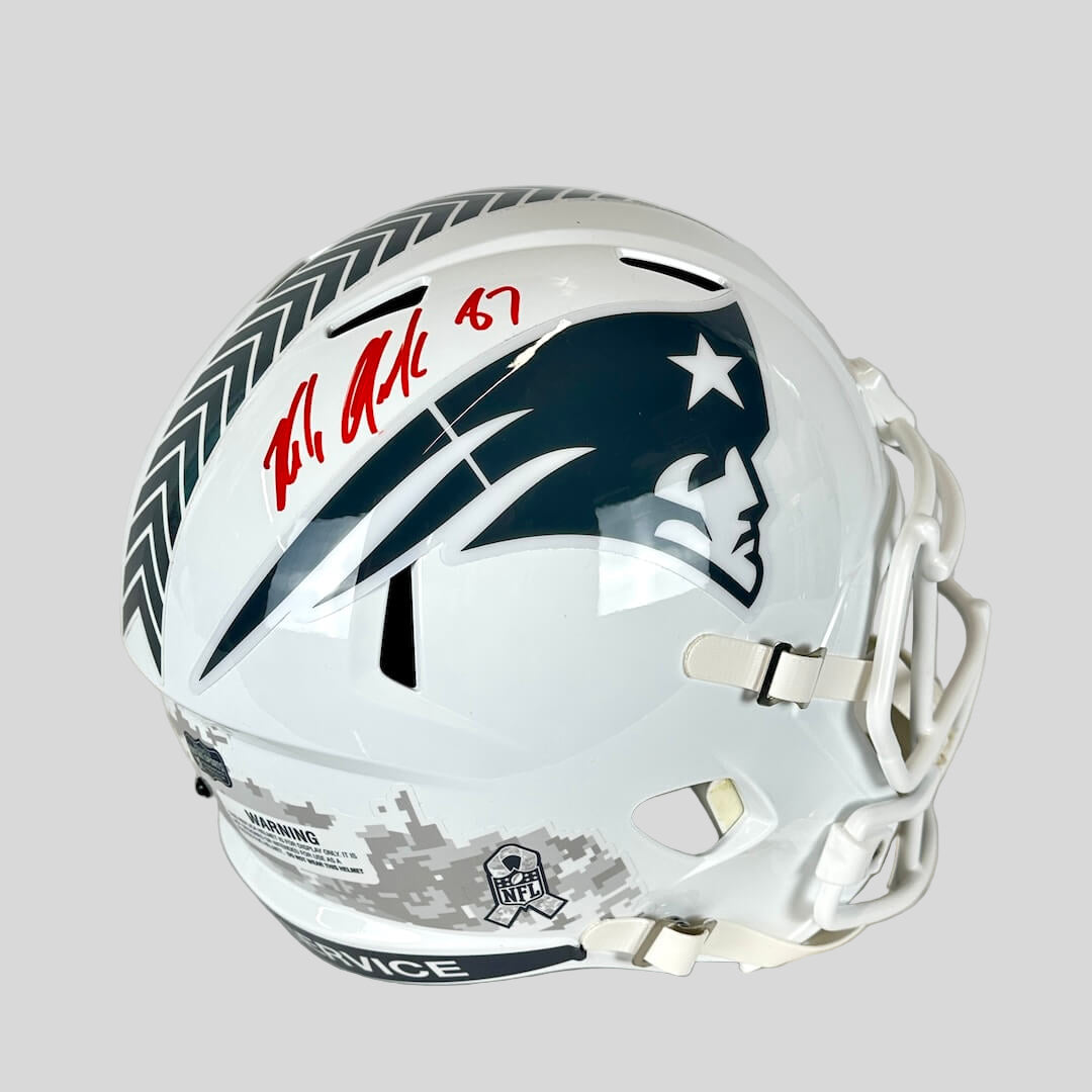 Signed white football helmet with Patriots logo against gray background.