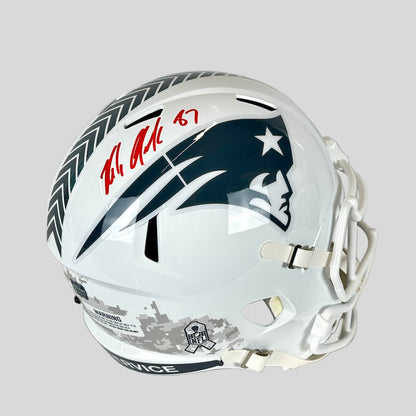 Signed white football helmet with Patriots logo against gray background.