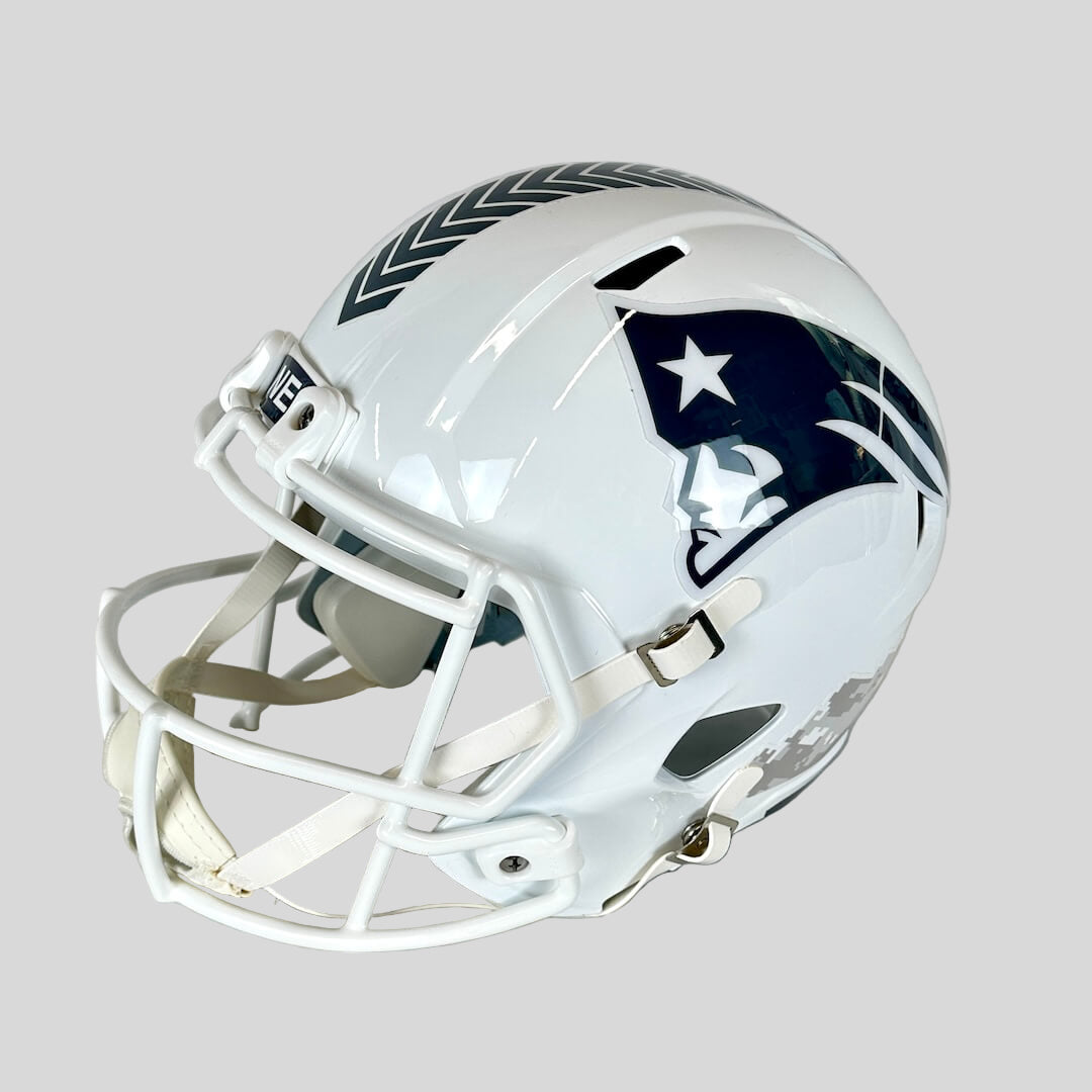 White football helmet with Patriots logo against gray background.
