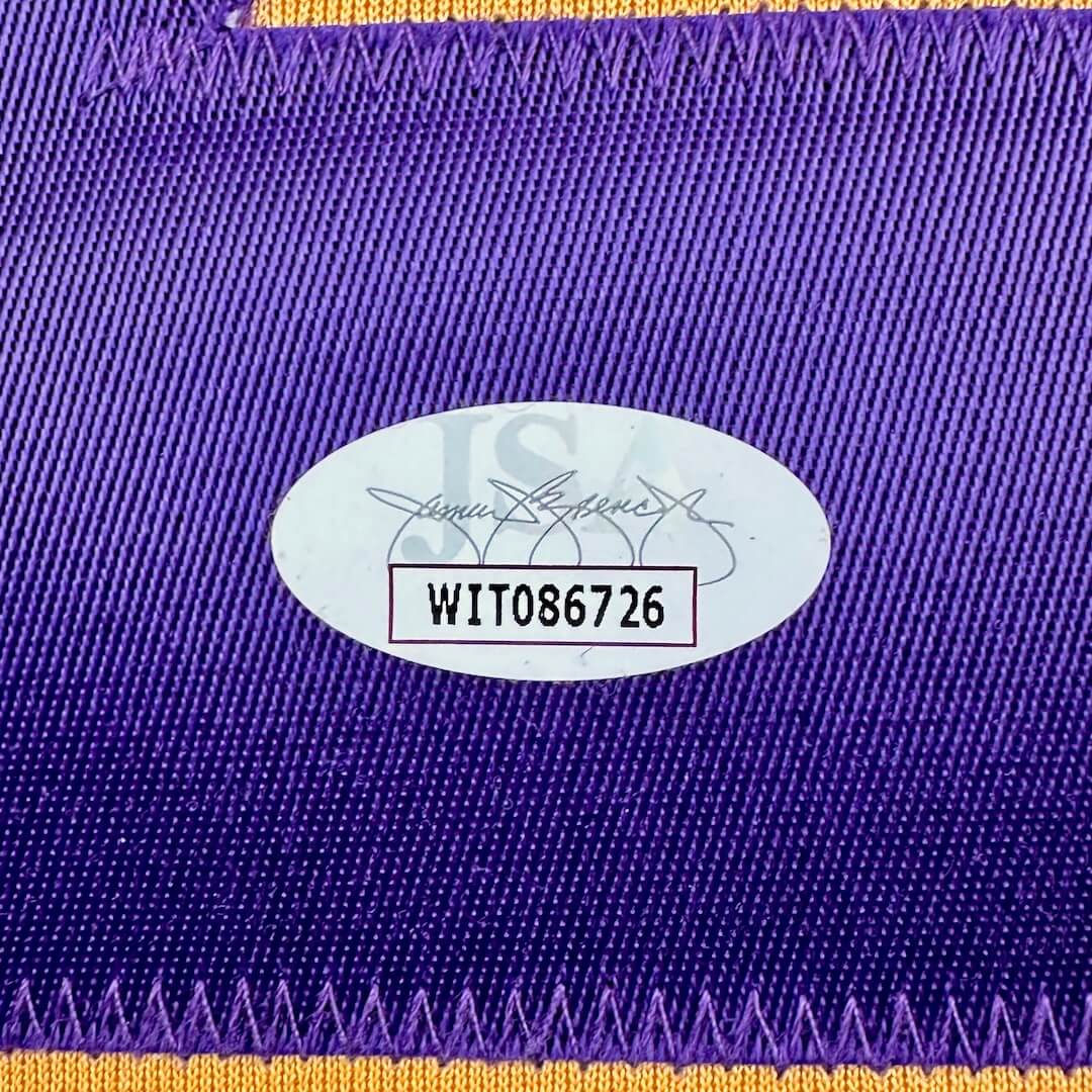 Close-up of a purple fabric with a gold border and an authenticataion label with text and numbers.