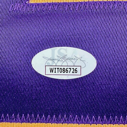 Close-up of a purple fabric with a gold border and an authenticataion label with text and numbers.