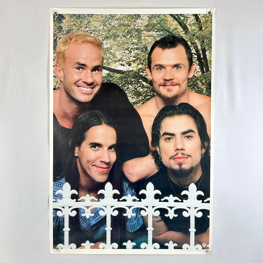Four men posing together with a white picket fence and trees in the background