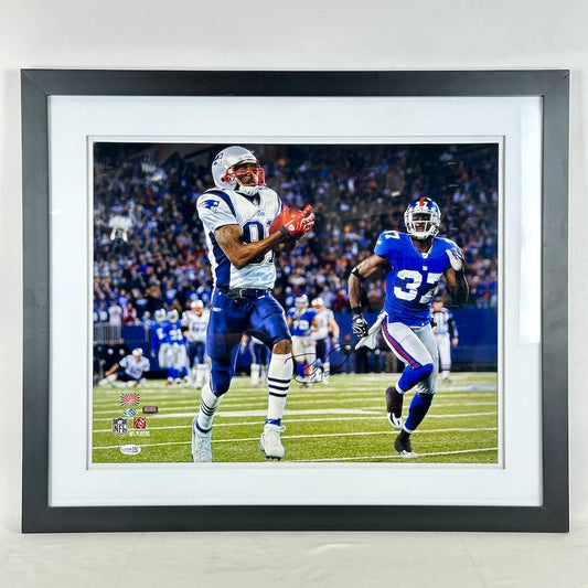 A framed sports photograph of NFL player Randy Moss on the field, presented in a black frame with a white mat.