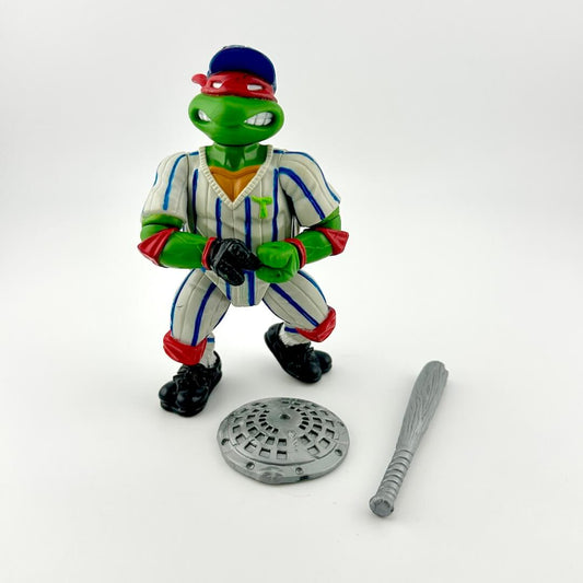 Toy figure of a turtle in a baseball uniform with a bat and base on a white background
