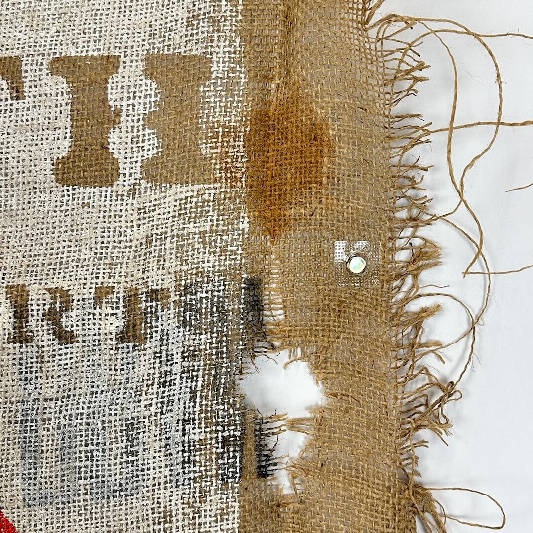 Close-up of a burlap fabric with frayed edges and printed text.