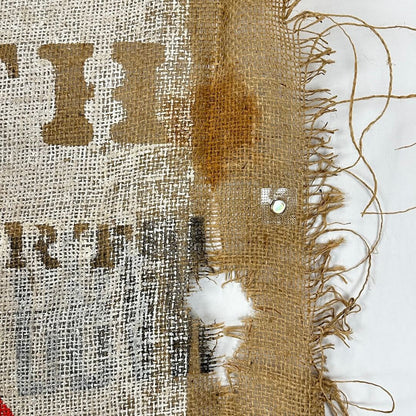 Close-up of a burlap fabric with frayed edges and printed text.