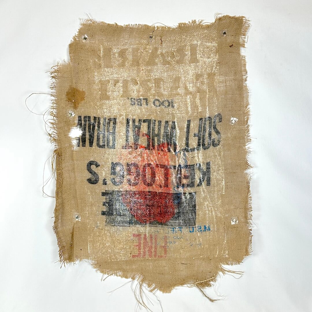 Rustic burlap sack with printed text and branding on a white background