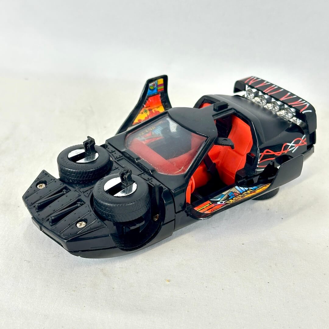 A black toy sports car with orange interior seats, flame decals, and a clear windshield.
