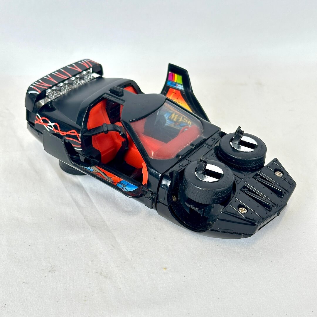 A vintage black toy sports car with orange interior seats.