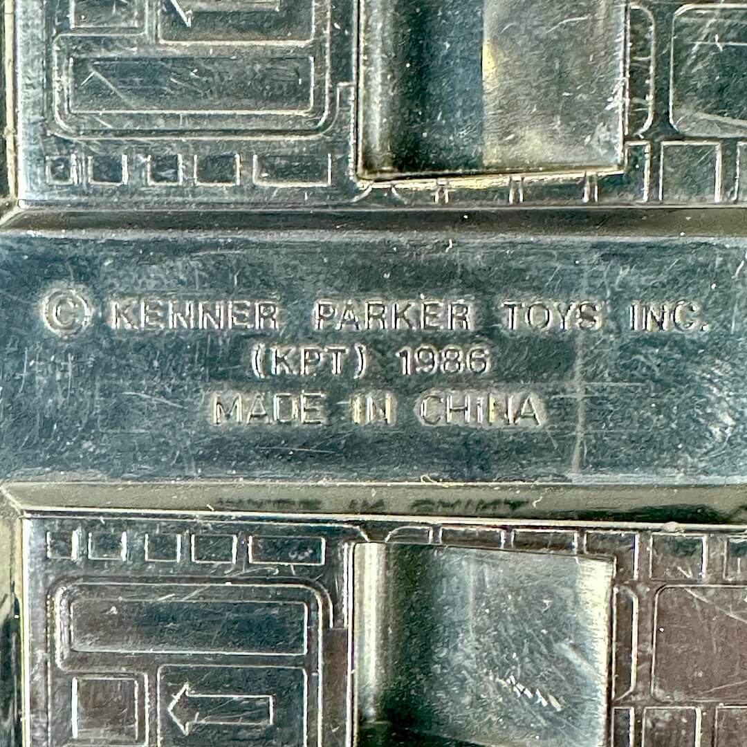Close-up of a dark metallic toy packaging or box embossed with Kenner Parker Toys Inc. 