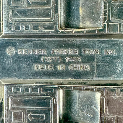 Close-up of a dark metallic toy packaging or box embossed with Kenner Parker Toys Inc. 