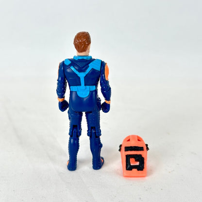 A vintage blue action figure shown from the back, standing next to an orange helmet on a plain white background.