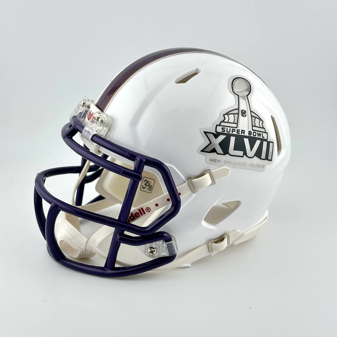 White football helmet with dark blue face mask and Super Bowl XLVII logo on a light gray background