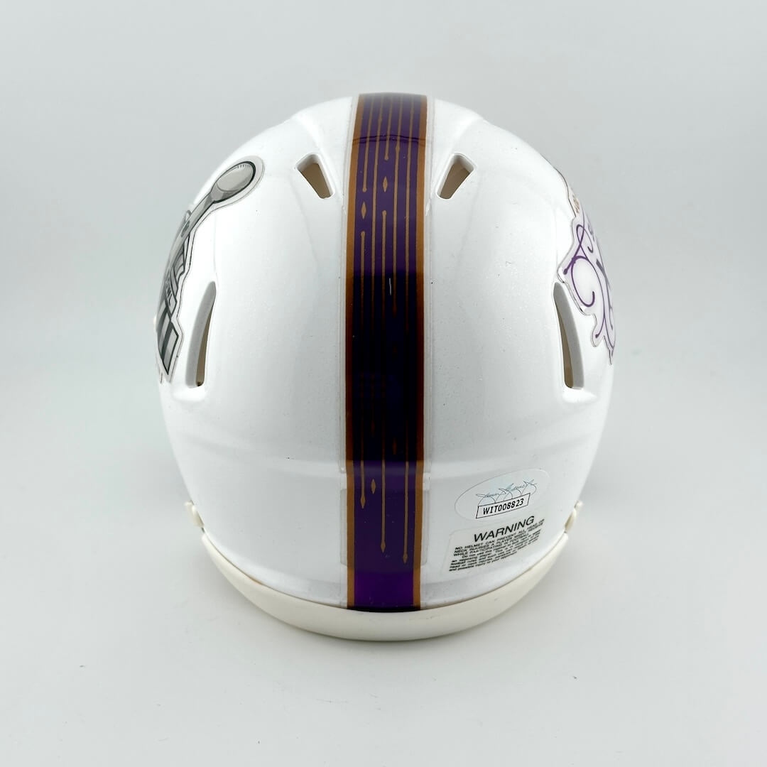 Backside of white mini helmet with purple stripe down center on light gray background. 