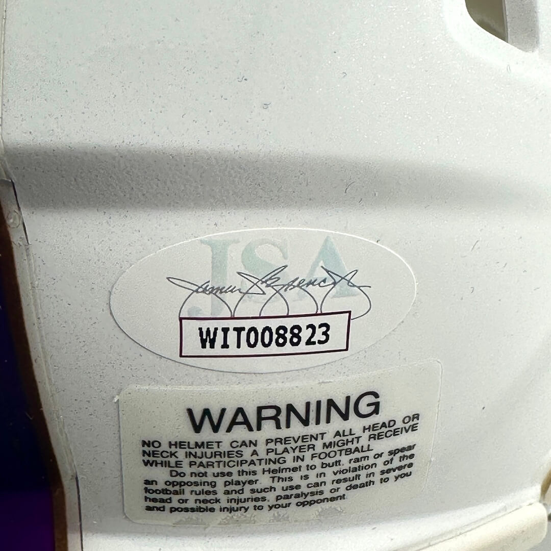 Close-up of authentication sticker by JSA on white mini helmet. 