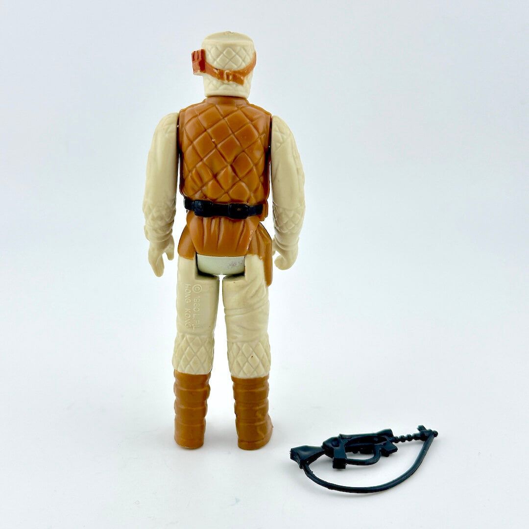 Action figure in beige outfit with brown vest and boots with weapon on white background. 