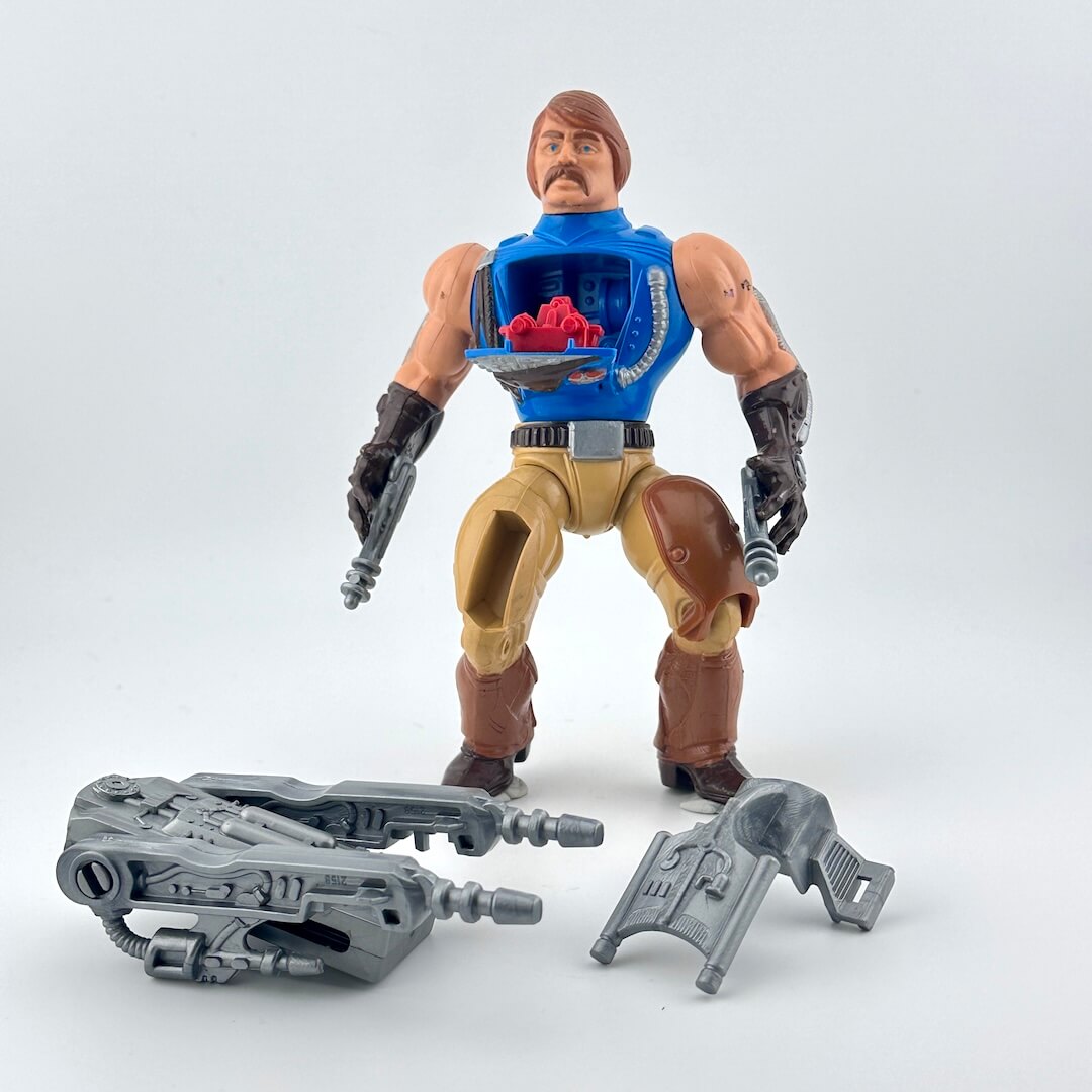 Action figure with blue vest and brown pants on a white background with gray accessories.